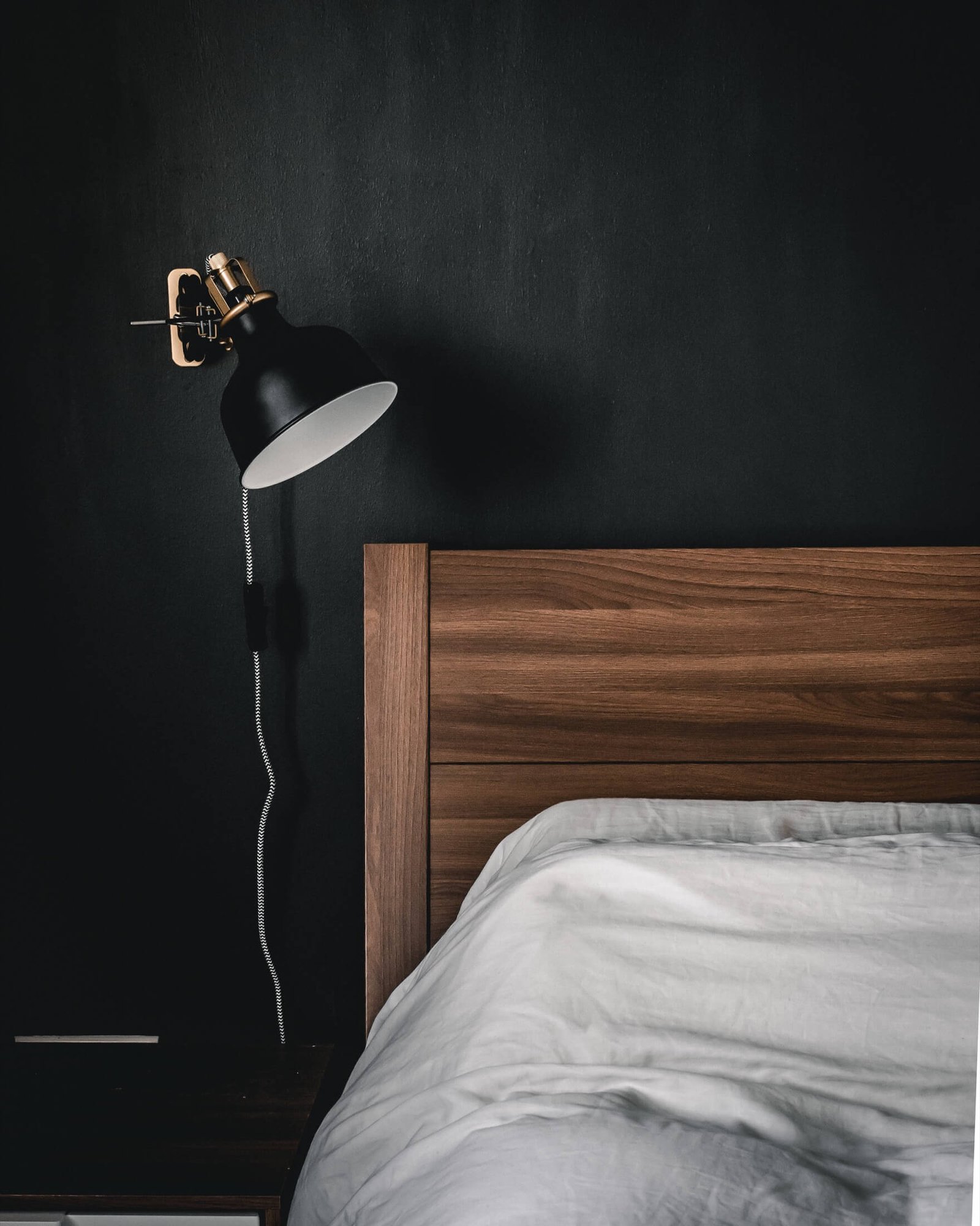 Moody suite interior with walnut headboard and brass reading lamp